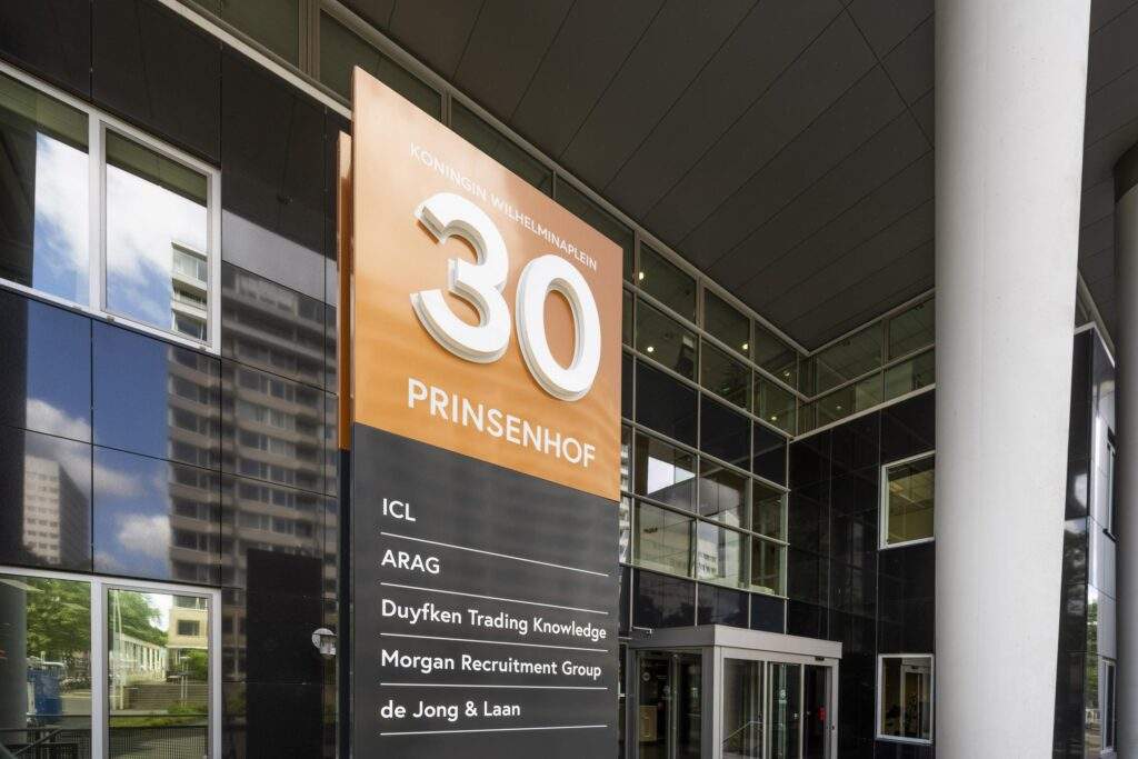 Ingang van het kantoorgebouw Prinsenhof aan het Koningin Wilhelminaplein 30 met een overzicht van de gevestigde bedrijven.